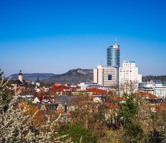 Stadtansicht Jena mit modernen und historischen Gebäuden unter klarem Himmel.